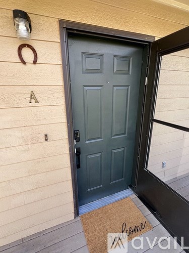 A grey door with a mat that says "welcome" on it.
