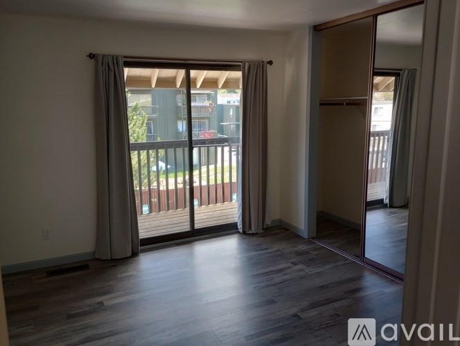 A room with wooden floors and sliding glass doors leading to a balcony.