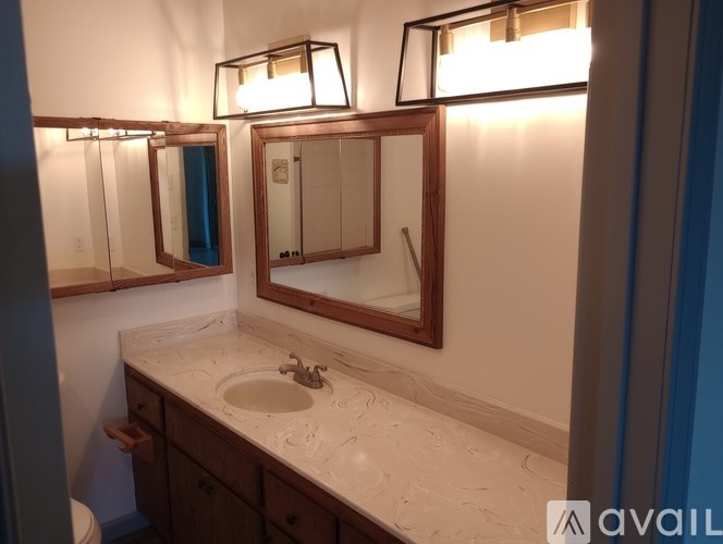 A bathroom with a sink, mirror, and lighting fixtures.
