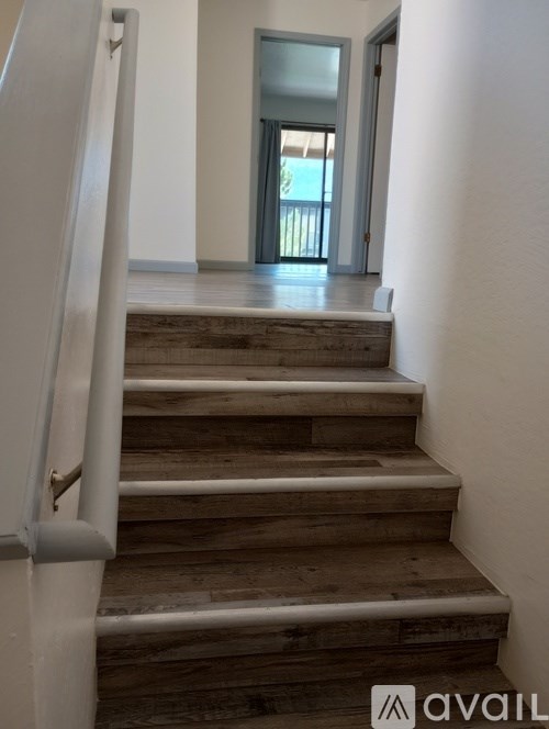 A set of stairs with a white railing lead to a doorway.