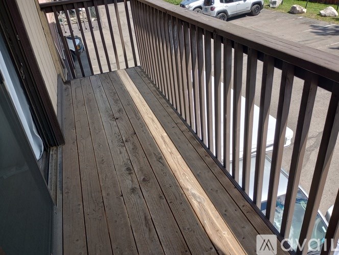 A wooden deck with a railing and a glass door.