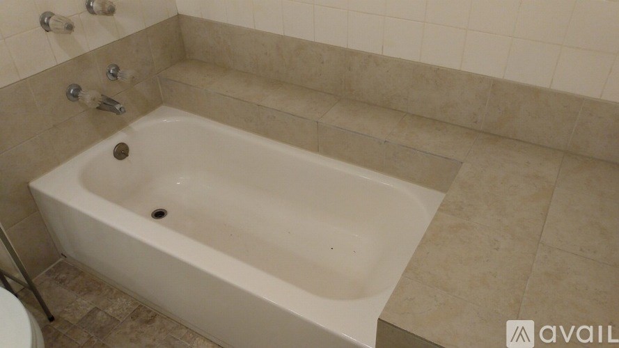 A white bathtub is in a bathroom with beige tiles.