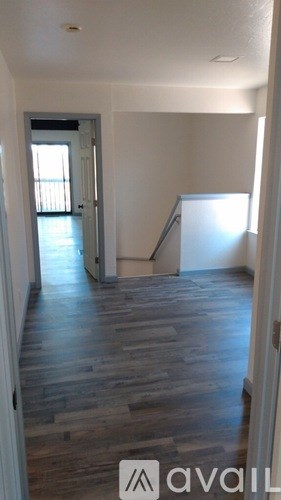 A room with wooden flooring and a doorway leading to another room.