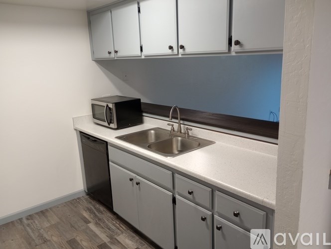 A kitchen with a sink, microwave, and cabinets.