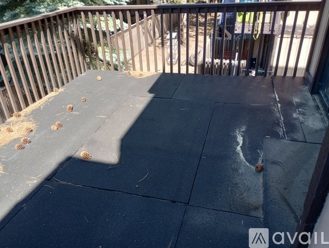 A patio with a black tiled floor and a wooden railing.