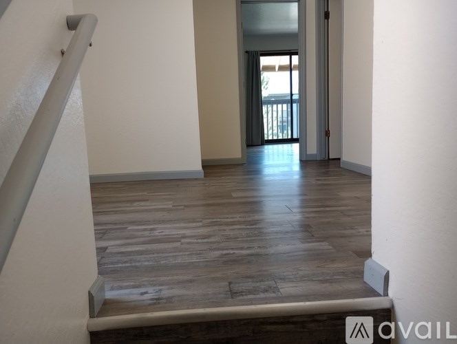 A room with wooden flooring and a staircase leading to a balcony.