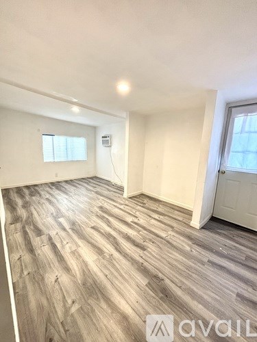A room with wooden flooring and white walls.