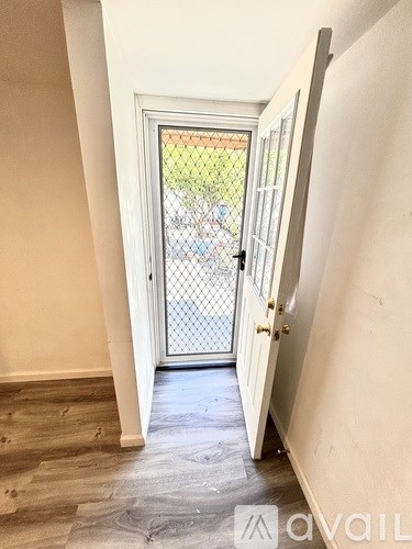 A hallway with a door leading outside.