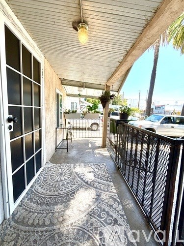 A balcony with a black railing and a patterned floor mat.