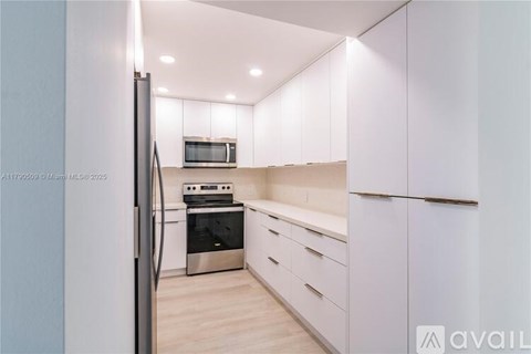 A modern kitchen with white cabinets and stainless steel appliances.
