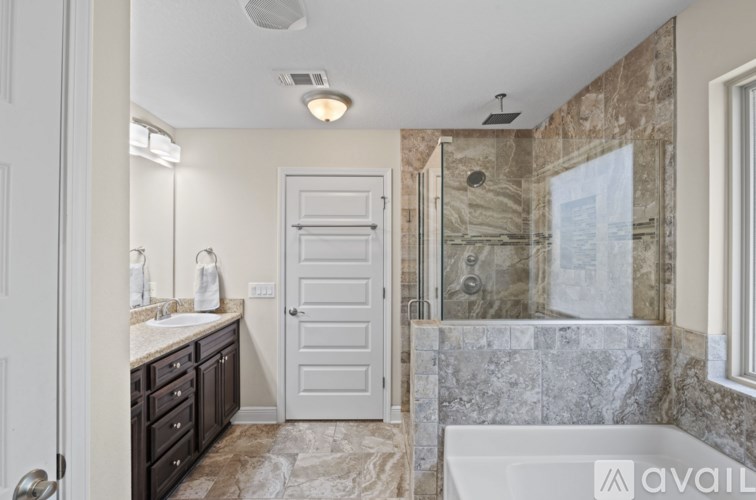 A bathroom with a marble tile shower and a white bathtub.