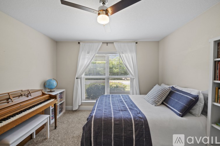 A bedroom with a bed, a piano, and a window with curtains.