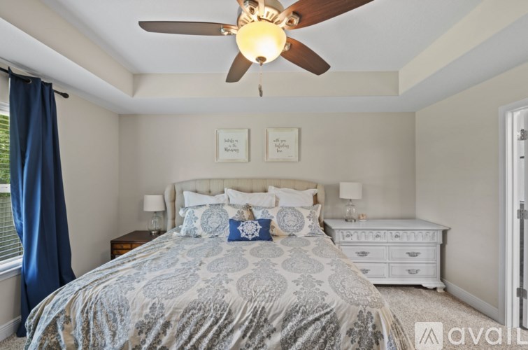 A bedroom with a large bed and a ceiling fan.