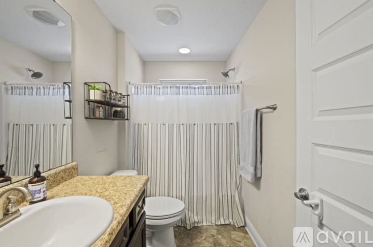A bathroom with a sink, toilet, and shower curtain.