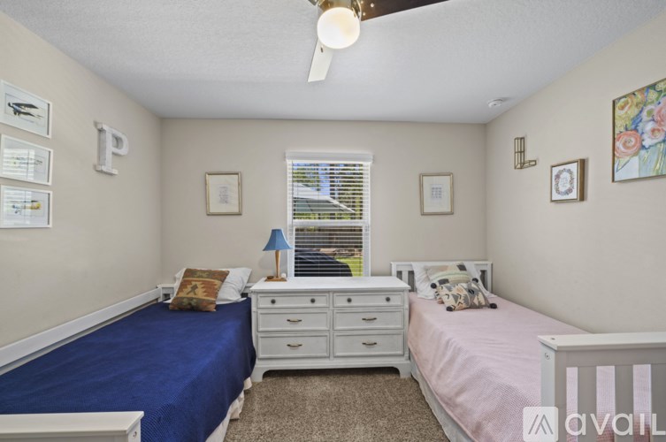 A bedroom with two beds and a ceiling fan.