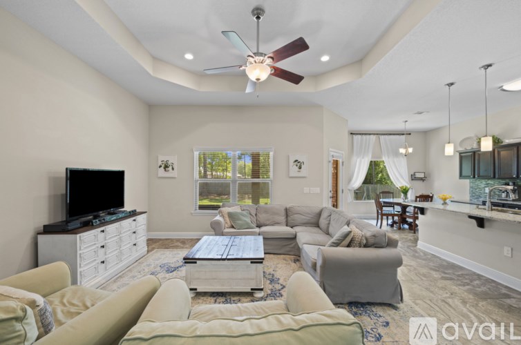 A living room with a television, couches, and a ceiling fan.