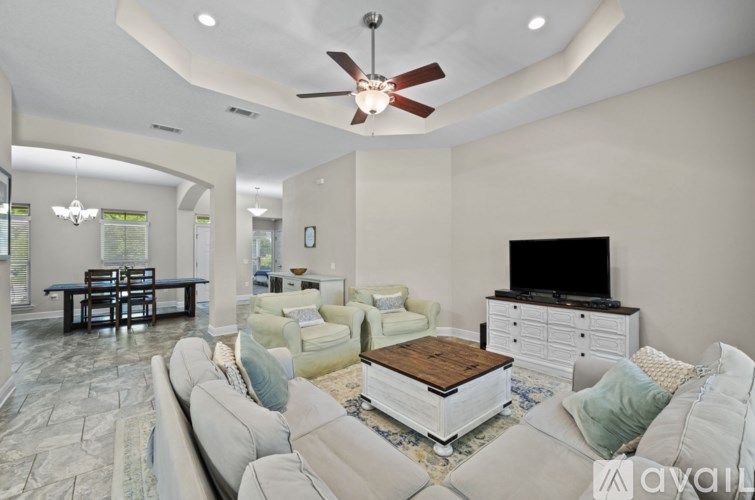A living room with a white couch, a wooden coffee table, and a flat screen TV.