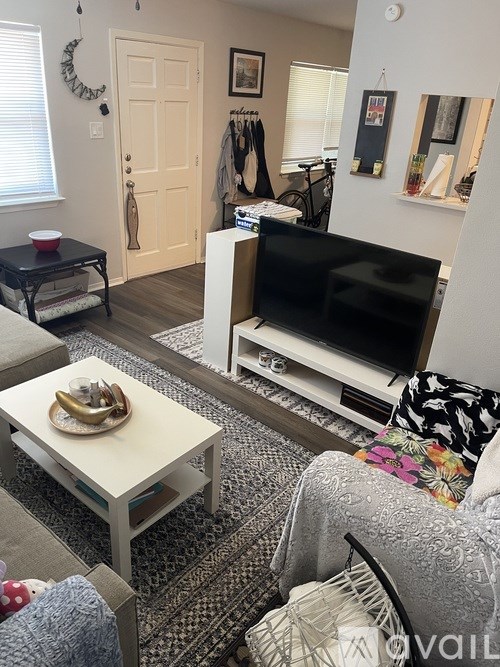 A living room with a black TV and a white coffee table.