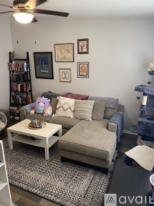 A living room with a grey couch, a coffee table, and a ceiling fan.