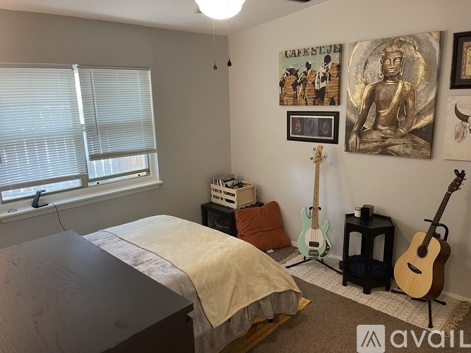 A bedroom with a bed, guitar, and a picture of a Buddha on the wall.