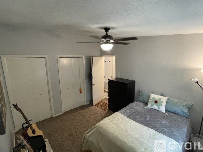 A bedroom with a bed, dresser, and guitar.