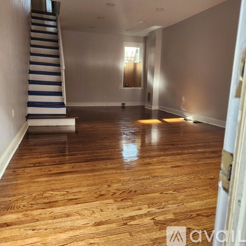 A room with wooden flooring and a staircase with blue and white stripes.