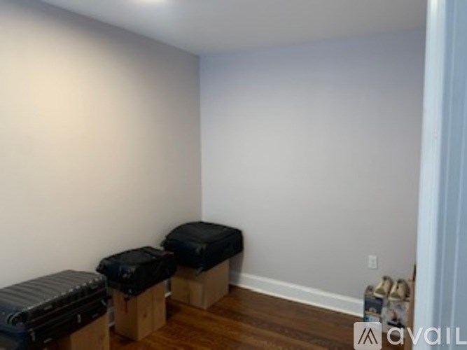 A room with a white wall and a wooden floor with three black ottomans.