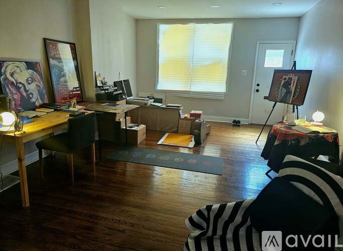 A room with a desk, chair, and painting on the wall.