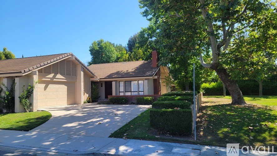 A house with a driveway and a tree in front.