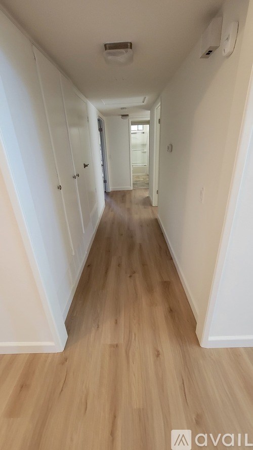 A long hallway with wood floors and white walls.