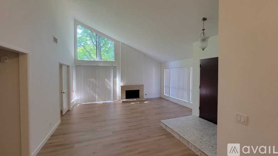A spacious living room with a fireplace and large windows.