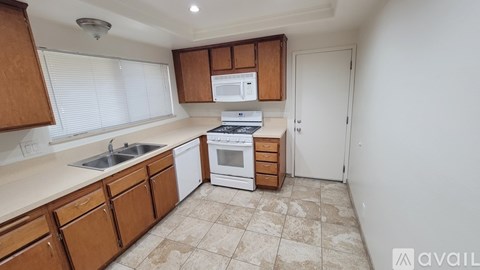 A kitchen with wooden cabinets and a white dishwasher.