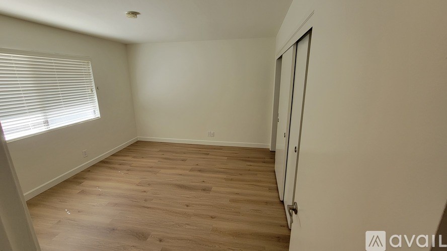 A room with wooden flooring and a window with blinds.