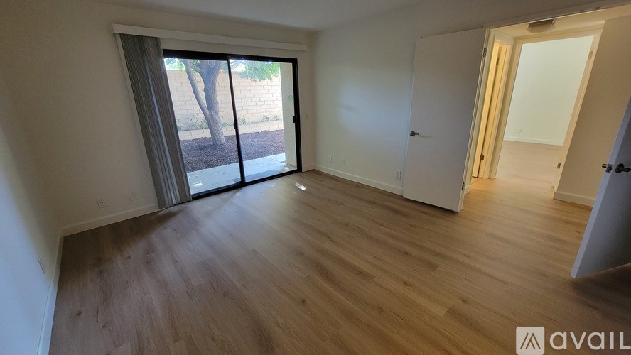 A room with wooden flooring and a sliding glass door leading outside.