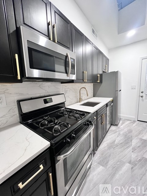A kitchen with black cabinets and a stove top oven.