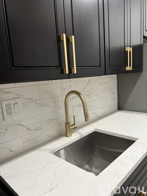 A kitchen with black cabinets and a marble countertop.
