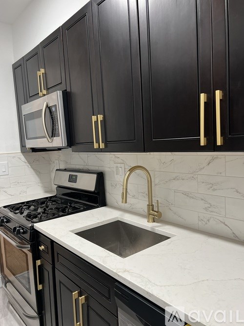 Black cabinets with gold handles and a marble countertop.