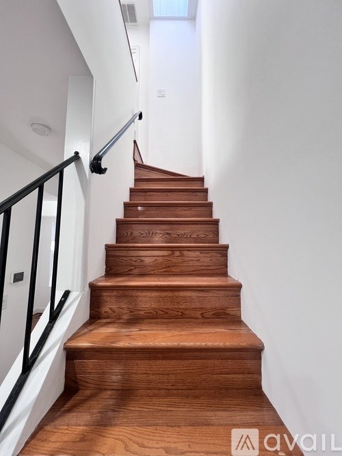 A wooden staircase with a black handrail.