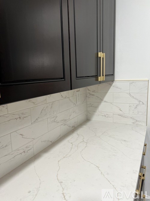 A kitchen with dark brown cabinets and marble countertops.