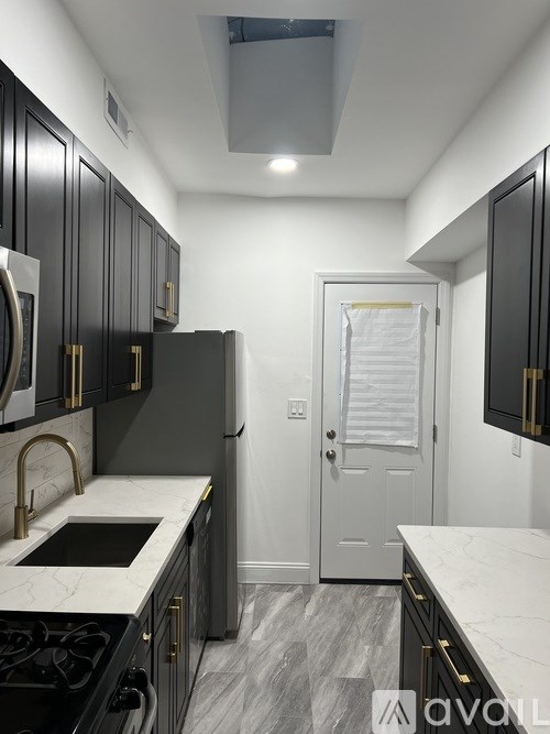 A kitchen with black cabinets and a white door.