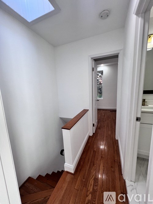 A hallway with wooden floors and white walls.