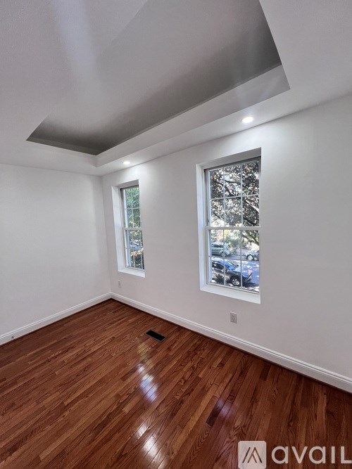 A room with wooden floors and a window showing a tree outside.