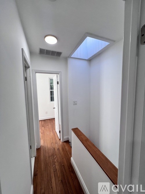 A hallway with a skylight and wood flooring.