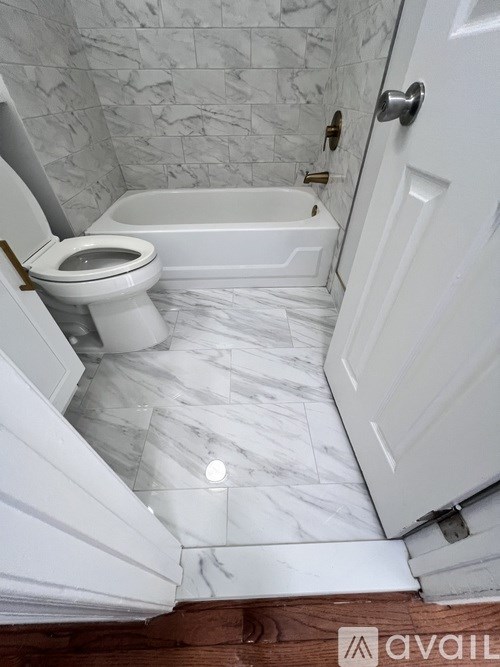 A white toilet sits in a marble bathroom.