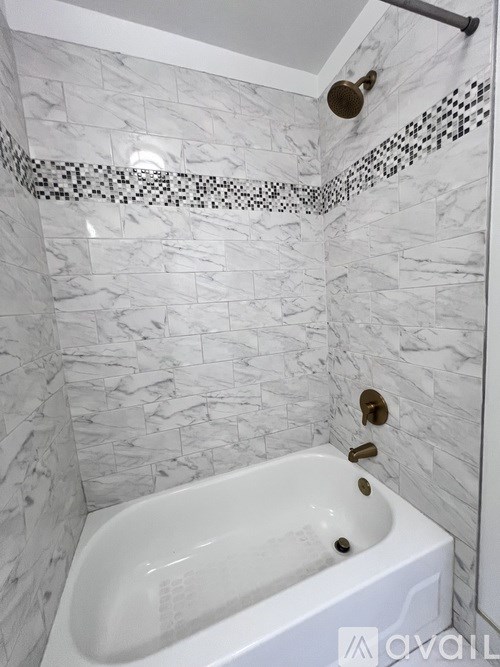 A white bathtub with a marble tile wall behind it.
