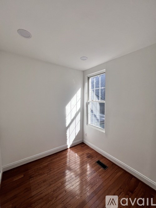 A room with wooden floors and a window letting in sunlight.