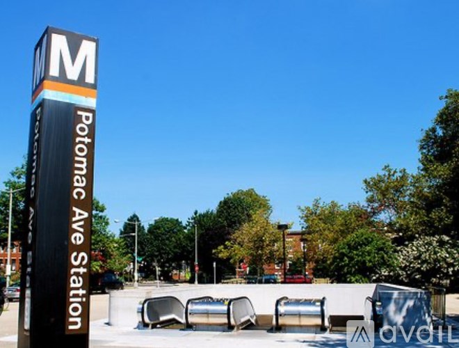 A tall sign with a letter M on it stands in front of a row of benches.