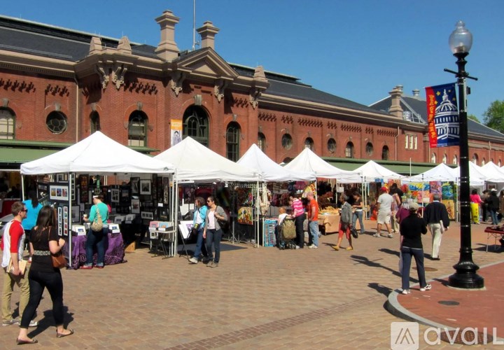 A busy outdoor market with white tents and people shopping.