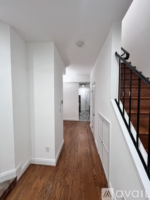 A long hallway with wood floors and white walls.