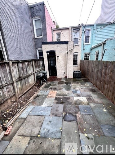 A backyard with a black door and a tiled floor.